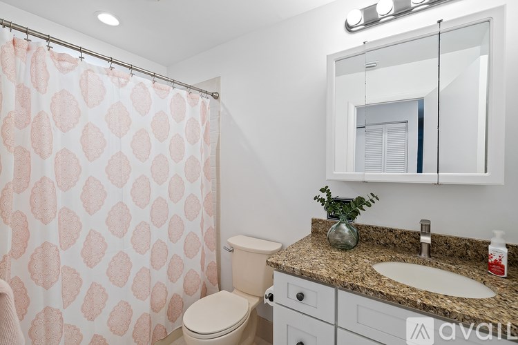 A bathroom with a pink shower curtain and a granite countertop.
