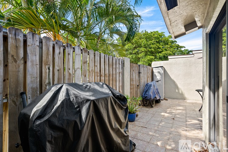 A patio with a black tarp covering a chair.