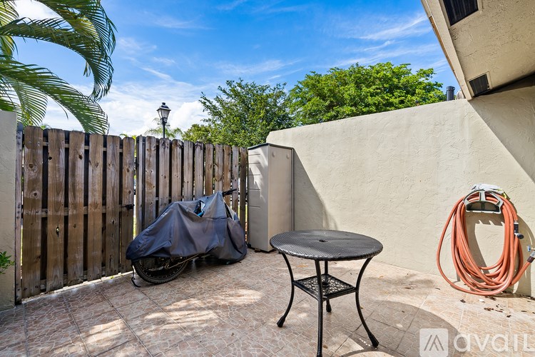 A patio with a table, a hose, and a wooden fence.
