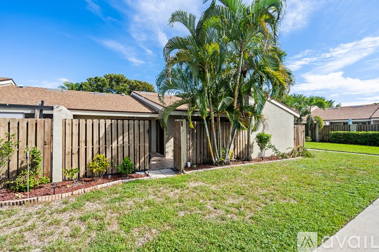 A house with a wooden fence and a tree in front.