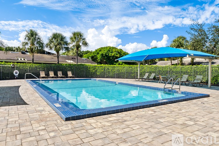 A swimming pool surrounded by a black fence and a blue umbrella.