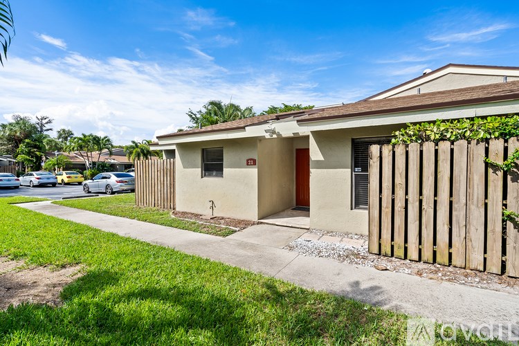 A small house with a red door is surrounded by a wooden fence.