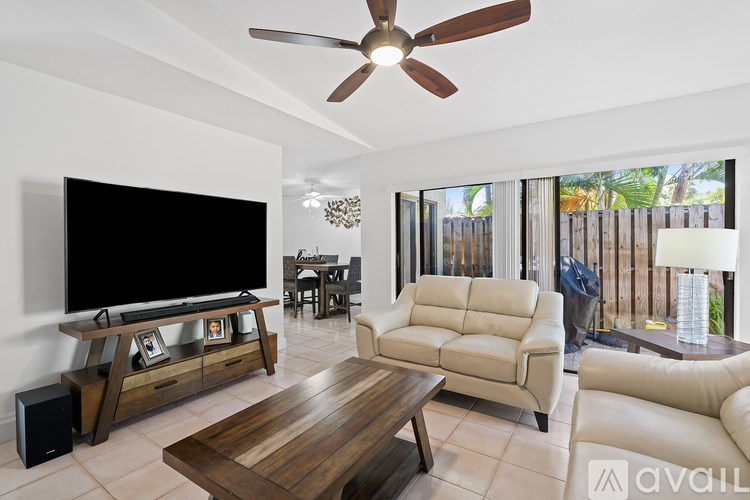 A living room with a television, a couch, a coffee table, and a ceiling fan.