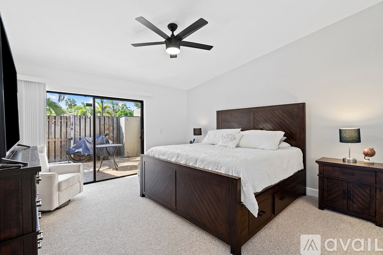 A bedroom with a large bed, a ceiling fan, and a sliding glass door leading to a balcony.