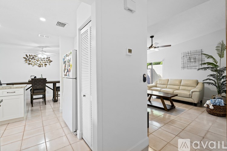 A modern kitchen with a dining table and chairs is visible through a partially opened door.