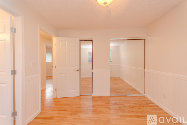 A spacious room with wooden floors and white walls.