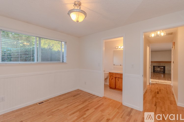 A room with wooden floors and a window with blinds.