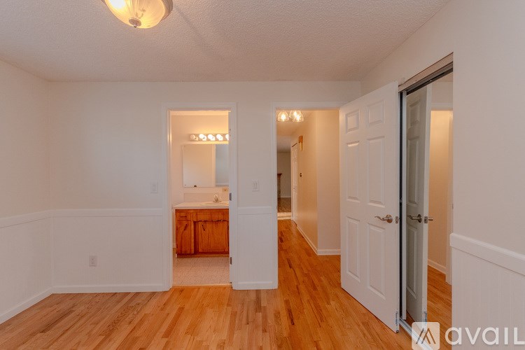 A room with wooden floors and white walls, with a door on the right side.