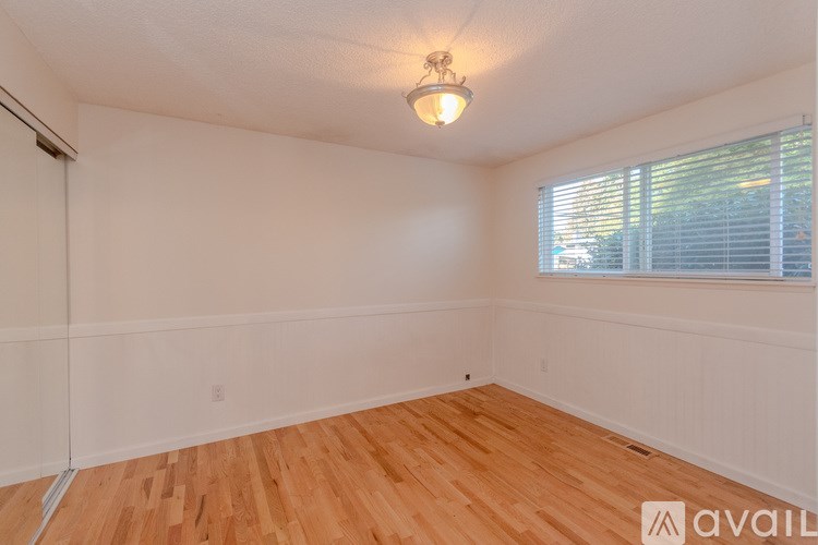 A room with wooden flooring and a window with blinds.