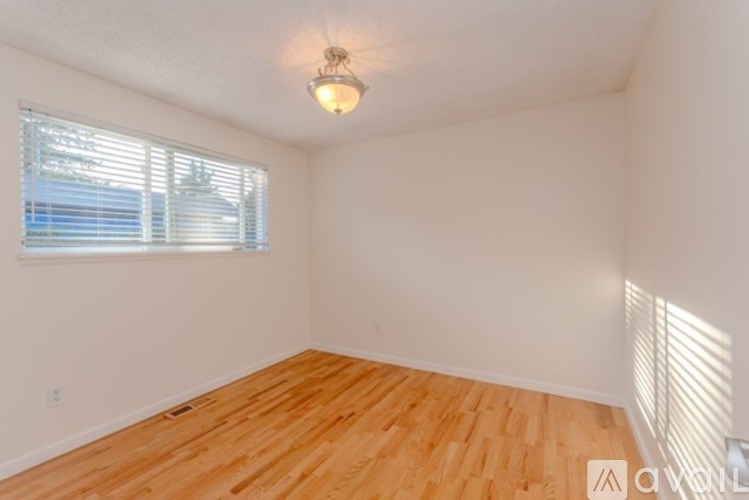 A room with wooden flooring and a window with blinds.