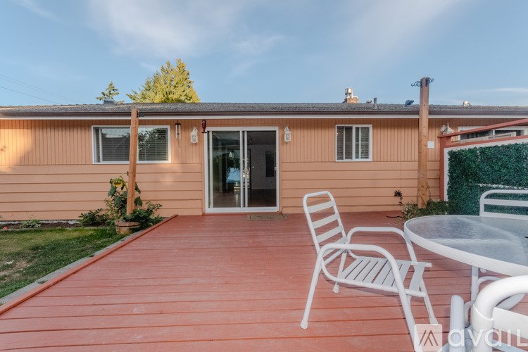 A wooden deck with a table and chairs is in front of a house.