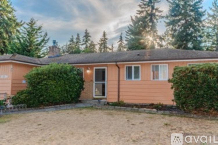 A house with a brown roof and a white door is surrounded by greenery.