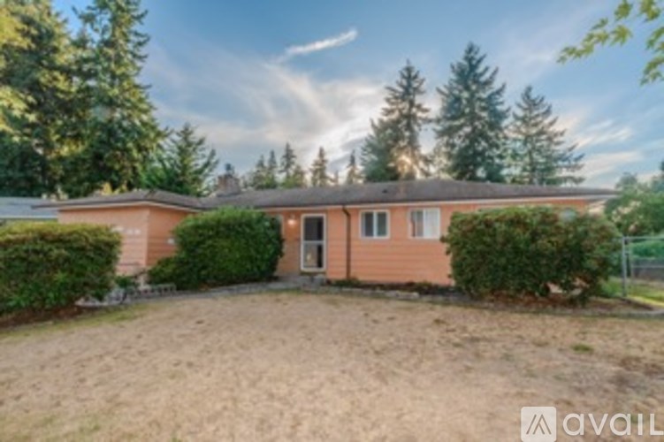 A house with a brown roof and a brown fence is surrounded by green trees.