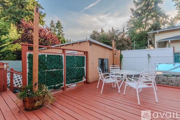 A wooden deck with a table and chairs and a pool in the backyard.