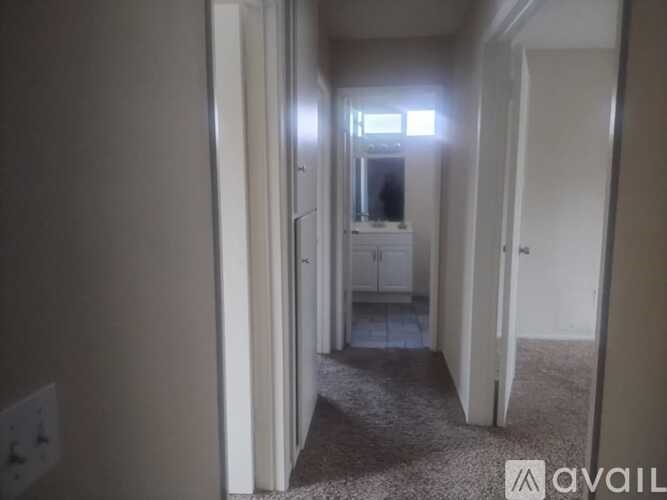 A hallway with a carpeted floor and white walls.
