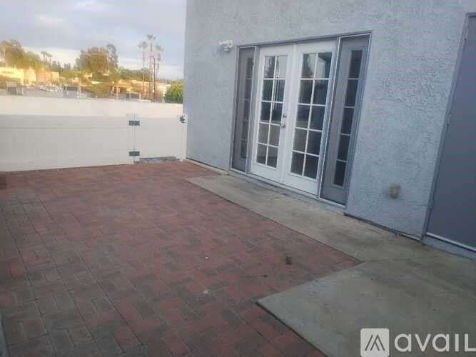 A patio with a brick patterned floor and a white door with a glass window.