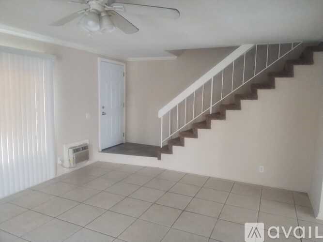 A room with a staircase, a ceiling fan, and a door.