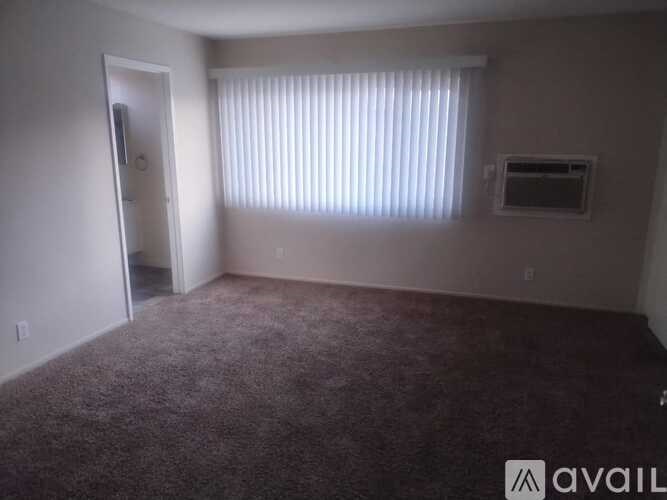 A room with a carpeted floor and a window with blinds.