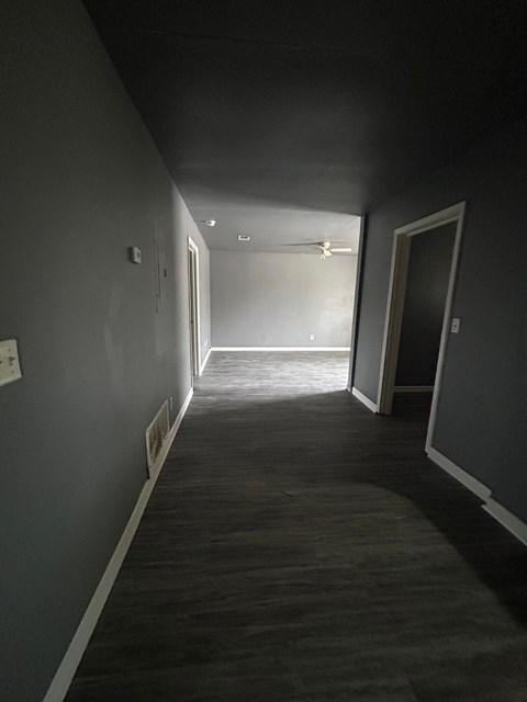 A long, narrow hallway with a door on the right and a window on the left.