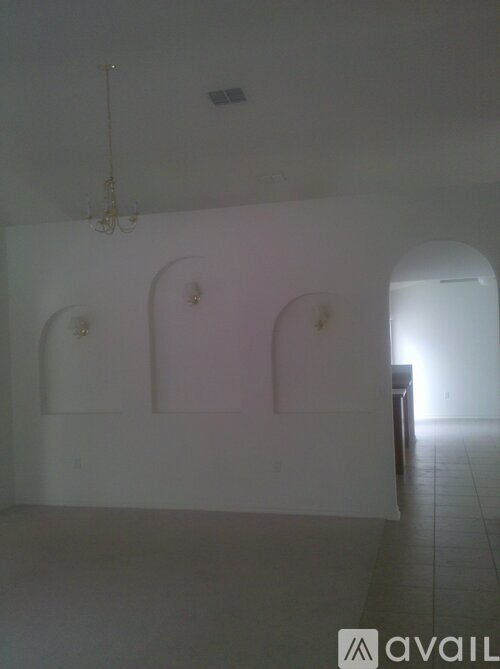 A room with a chandelier and two arched doorways.