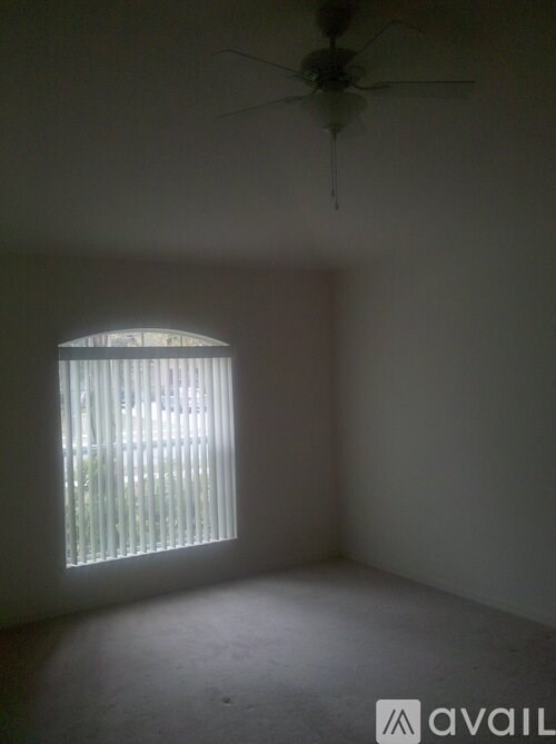 A room with a ceiling fan and a window with blinds.