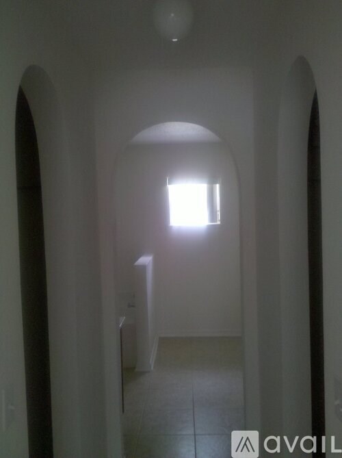 A long hallway with arches on the sides and a light at the end.