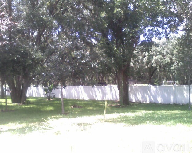 A white fence is behind some trees.
