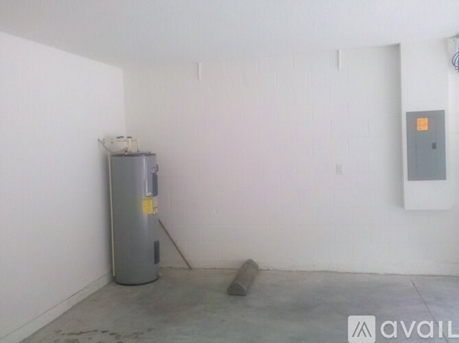 A room with a white wall and a grey water heater.