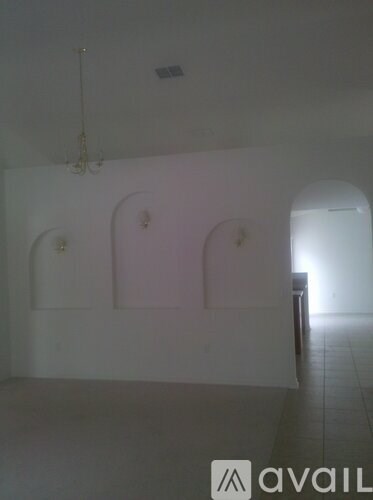 A room with a chandelier and arched windows.