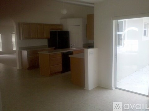 A kitchen with wooden cabinets and a black fridge is available for rent.