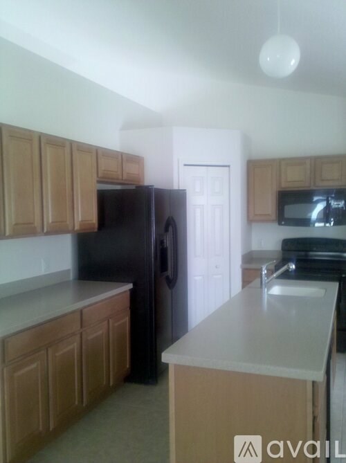A kitchen with wooden cabinets and a black refrigerator.