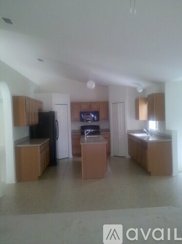 A kitchen with wooden cabinets and appliances in a room with a tiled floor.