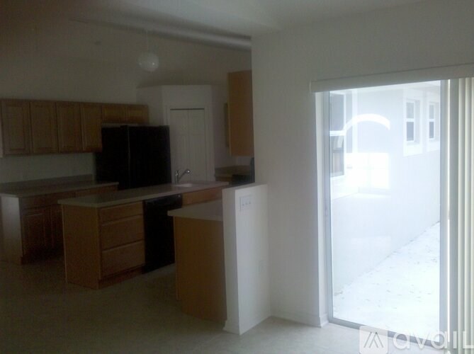 A kitchen with wooden cabinets and a black fridge.