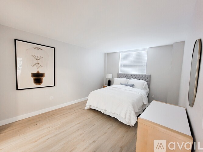 A bedroom with a white bed and a framed picture on the wall.