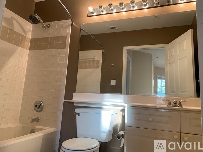 A bathroom with a white toilet, a bathtub, and a mirror.