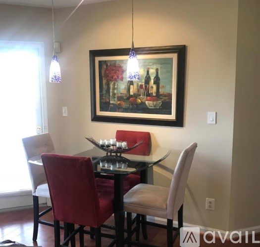 A dining room with a table set for two and a painting on the wall.