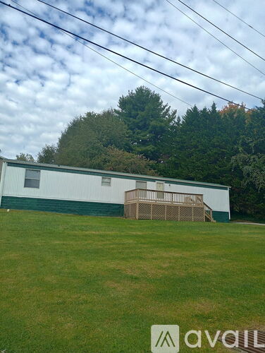 A white building with a green roof and a wooden fence in front of it.