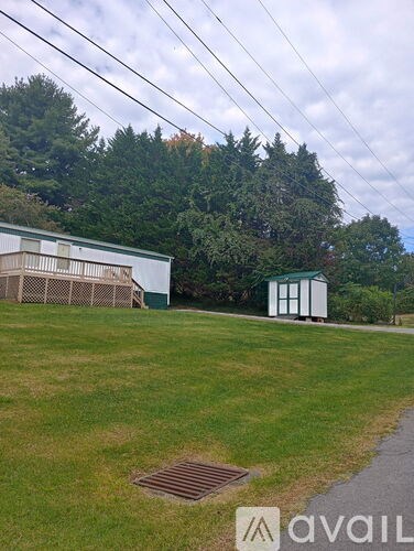 A grassy field with a white building and a small shed.