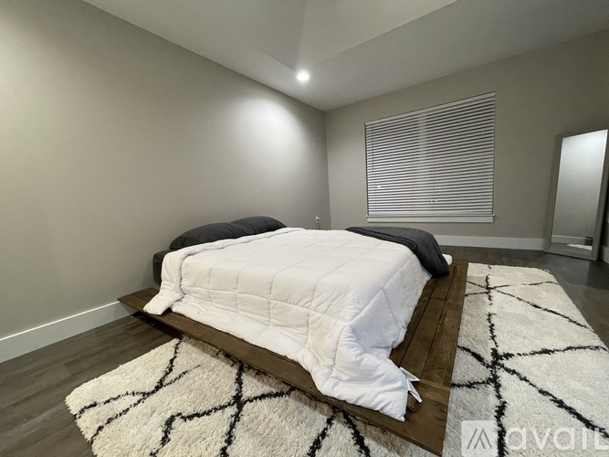 A bedroom with a white bedspread and a black and white rug.
