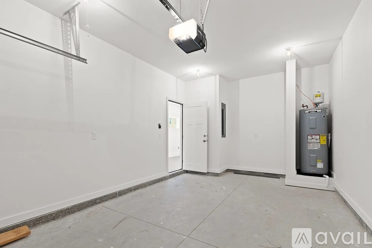 A spacious empty room with a door, a window, and a white wall.