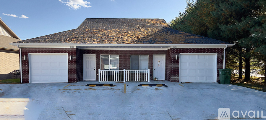 A two-car garage with a brick facade and a white picket fence.