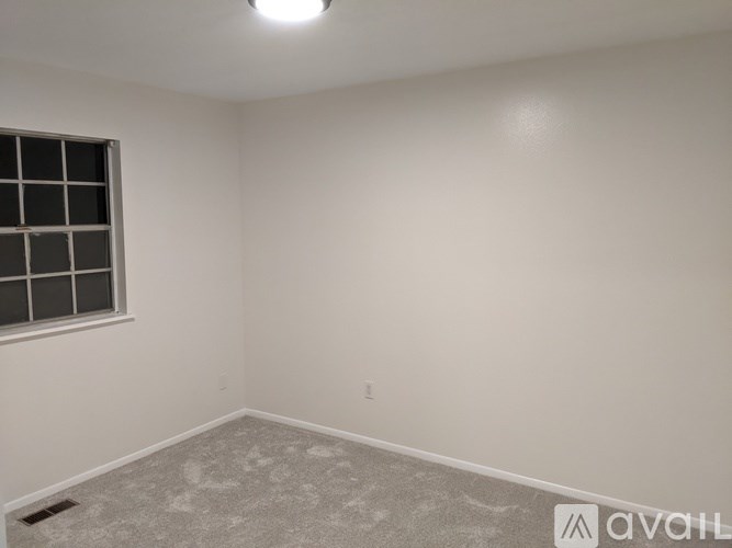 A room with a window and a carpeted floor.