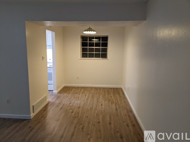 A room with wooden flooring and a window with bars on it.