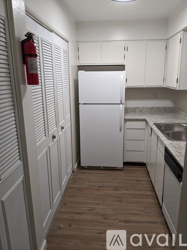 A kitchen with white cabinets and a white fridge.