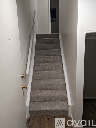 A staircase with a carpeted runner and a white railing.