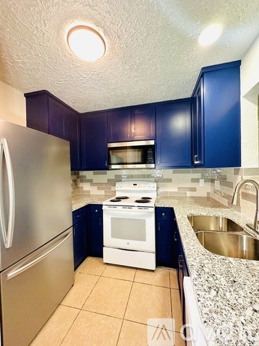 A kitchen with blue cabinets and a stainless steel refrigerator.