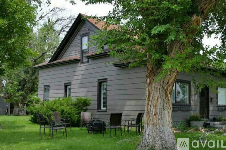 A house with a grey exterior and a tree in front of it.