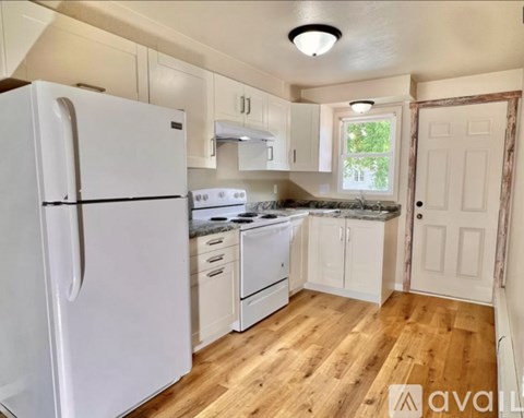 A kitchen with white appliances and wooden floors.