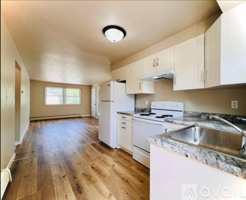 A kitchen with white appliances and wooden floors.