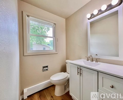 A bathroom with a toilet, sink, and mirror.